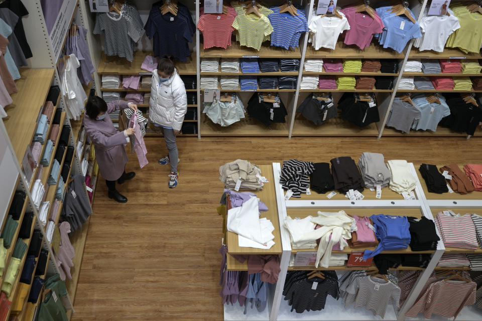 Women wearing face masks check on a clothing as they shop at a Uniqlo global flagship store in Beijing, Wednesday, March 1, 2023. Chinese leader Xi Jinping's agenda for the annual meeting of the ceremonial legislature: Revive the struggling economy by encouraging consumers to spend now that severe anti-virus controls have ended. Install a government of Xi loyalists to intensify the ruling Communist Party's control over the economy and society. (AP Photo/Andy Wong)