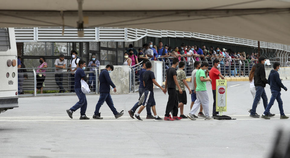 Several immigrants are escorted off an immigration bus on the Hidalgo International Bridge on Wednesday, June, 2, 2021 in Hidalgo, Texas. The congressional delegation from Texas and Arizona got a tour of the Texas-Mexico border in the Rio Grande Valley to get an update on the migrant surge in the region. (Delcia Lopez/The Monitor via AP)