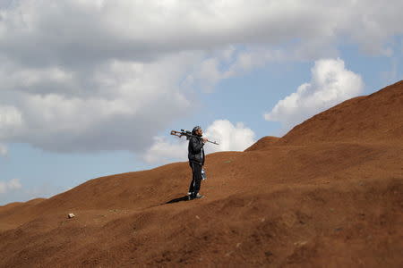 A rebel fighter from 'Jaysh al-Sunna' holds his weapon as he stands behind sand barricade in Tel Mamo village, in the southern countryside of Aleppo, Syria March 6, 2016. REUTERS/Khalil Ashawi