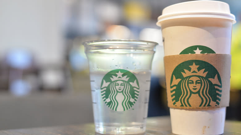 Starbucks water cup next to cup of coffee