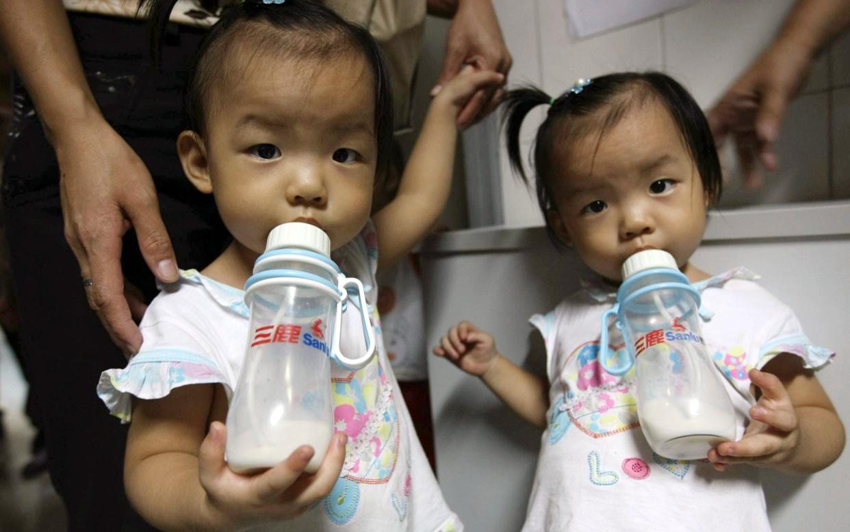 Two girls drink milk from Sanlu brand bottles while waiting to be checked for kidney stones at a children's hospital in Shenzhen, in south China's Guangdong province - Color China Photo)/AP