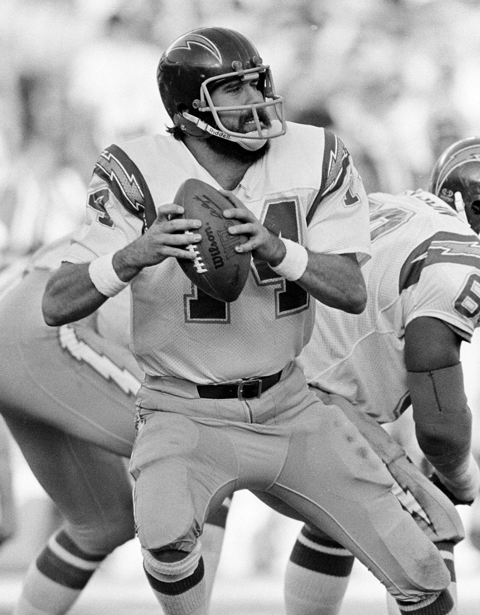 FILE - In this Dec. 27, 1982, file photo, San Diego Chargers quarterback Dan Fouts (14) looks downfield before releasing a pass against the Baltimore Colts during an NFL football game in San Diego. The biggest piece of San Diego's sports history is slowly being knocked down and ground to bits. Now the stadium is coming to an unceremonious end, leaving generations of fans feeling melancholy because, due to the coronavirus pandemic, they didn't get to say a proper goodbye to the place where they tailgated with gusto in the massive parking lot before cheering on the Chargers, Padres and Aztecs, or watched myriad other events and concerts. (AP Photo/Lenny Ignelzi, File)