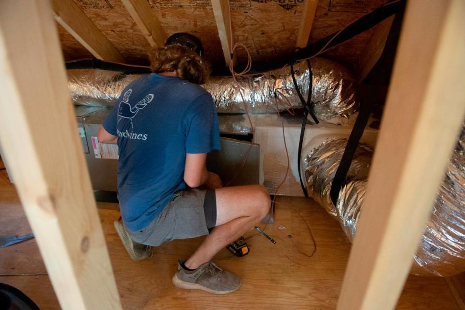 Trevor Todd, an employee of Airlogy of Mississippi, works to install an air conditioning system and ductwork at a new construction home in Biloxi on Thursday, Aug. 17, 2023.