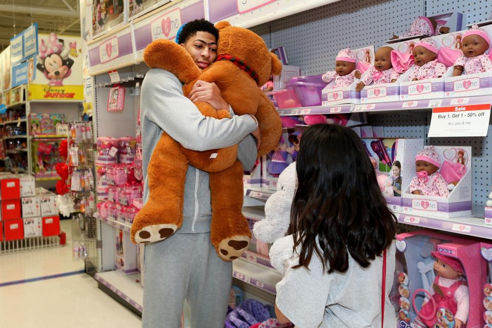 Anthony Davis embraces the holiday spirit, and a very large teddy bear, during a New Orleans Pelicans Shopping Spree event. (Getty Images)