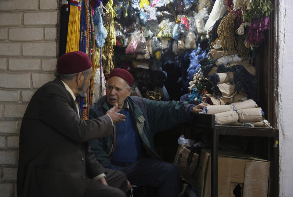 Tunisian vendors talk to each other outside their shop, in the Old City of Tunis, Tunisia, Thursday, March 28, 2019. Tunisia is cleaning up its boulevards and securing its borders for an Arab League summit that this country hopes raises its regional profile and economic prospects. Government ministers from the 22 Arab League states are holding preparatory meetings in Tunis all week for Sunday's summit. (AP Photo/Hussein Malla)