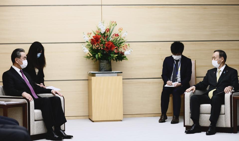 Japan's Prime Minister Yoshihide Suga, right, sits with China's Foreign Minister Wang Yi, left, at the start of their meeting in Tokyo, Wednesday, Nov. 25, 2020. (Behrouz Mehri/Pool Photo via AP)