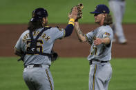 Milwaukee Brewers' Jacob Nottingham, left, high fives Josh Hader, right, in the ninth inning during a baseball game against the Cincinnati Reds in Cincinnati, Tuesday, Sept. 22, 2020. (AP Photo/Aaron Doster)