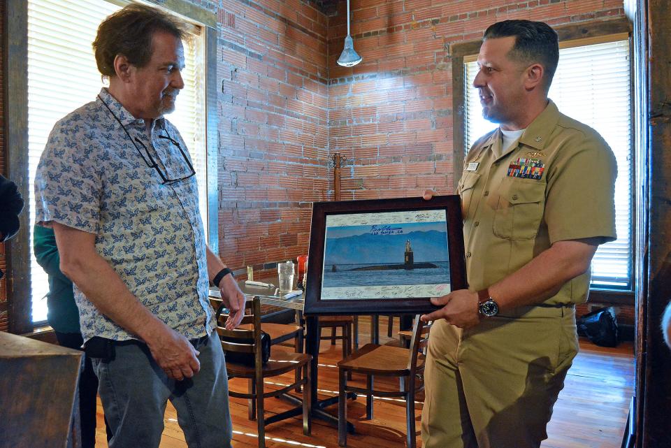 USS Columbia Cmdr. Brad Foster presents a photo Wednesday of the submarine with signatures from the officers and enlisted sailors to Tom Smith, owner of Flat Branch Pub and Brewing. Both the submarine and the restaurant are marking 30-year anniversaries. A similar photo was presented to Mayor Barbara Buffaloe, not pictured.