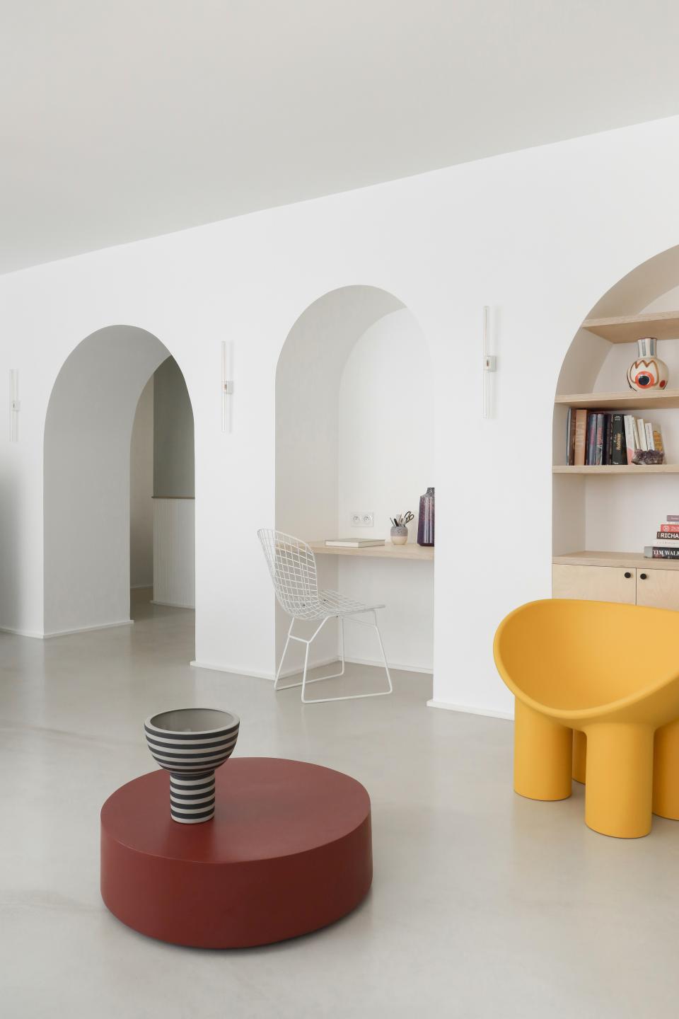 AFTER: One of the biggest changes to the home was this arched “living wall” created by the architects. The yellow Roly Poly chair by Faye Toogood adds a pop of color to the living room furnished with a Serax coffee table and vases by AYTM and LRNCE.