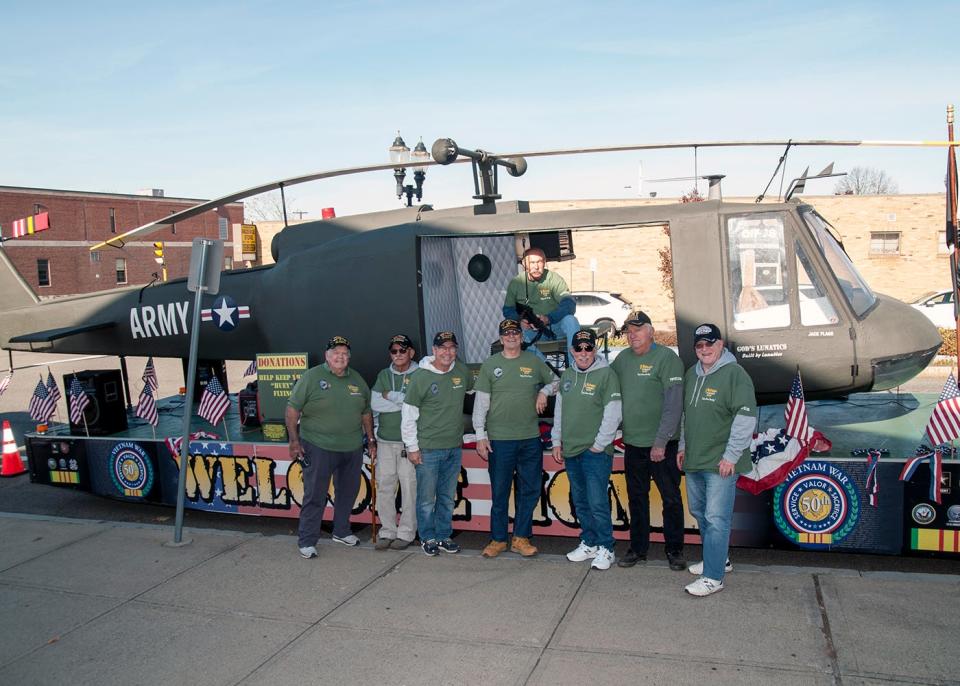 Vietnam War veterans stand next to the model Huey helicopter they built as part of the Huey Helicopter Group out of Plymouth.