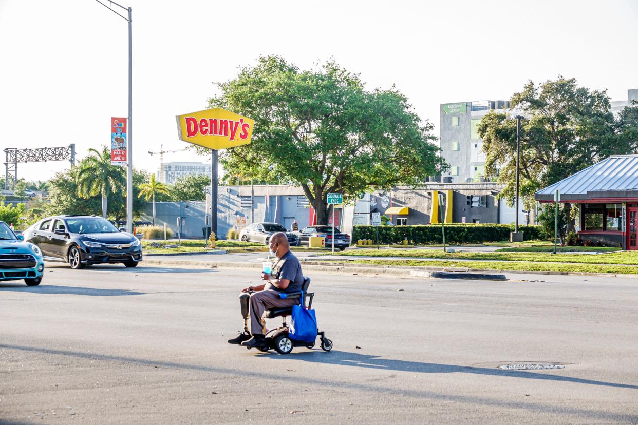 Miami, Florida, man in electric wheelchair crossing busy street.