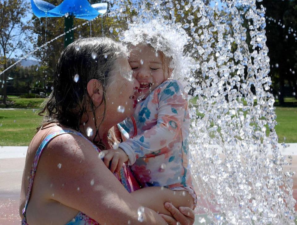 Ann Cole of Simi Valley holds her granddaughter Brooklyn Cole, 2½, as they enjoy the water pad at Rancho Tapo Community Park in Simi Valley while temperatures reached triple-digits on Wednesday.