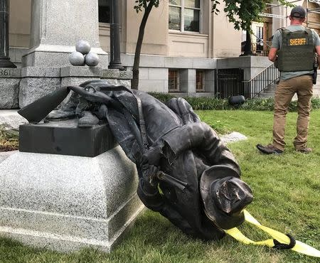 A Sheriff's deputy stands near the toppled statue of a Confederate soldier in front of the old Durham County Courthouse in Durham, North Carolina, U.S. August 14, 2017. REUTERS/Kate Medley