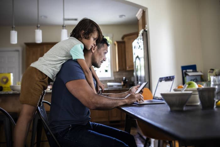 Father using laptop while son looks over his shoulder