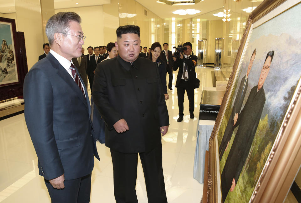 South Korean President Moon Jae-in, left, and North Korean leader Kim Jong Un look at a picture of themselves shaking hands as they arrive to attend a welcome banquet in Pyongyang, North Korea, Tuesday, Sept. 18, 2018. President Moon Jae-in began his third summit with North Korean leader Kim Jong Un on Tuesday with possibly his hardest mission to date — brokering some kind of compromise to keep North Korea's talks with Washington from imploding and pushing ahead with his own plans to expand economic cooperation and bring a stable peace to the Korean Peninsula. (Pyongyang Press Corps Pool via AP)