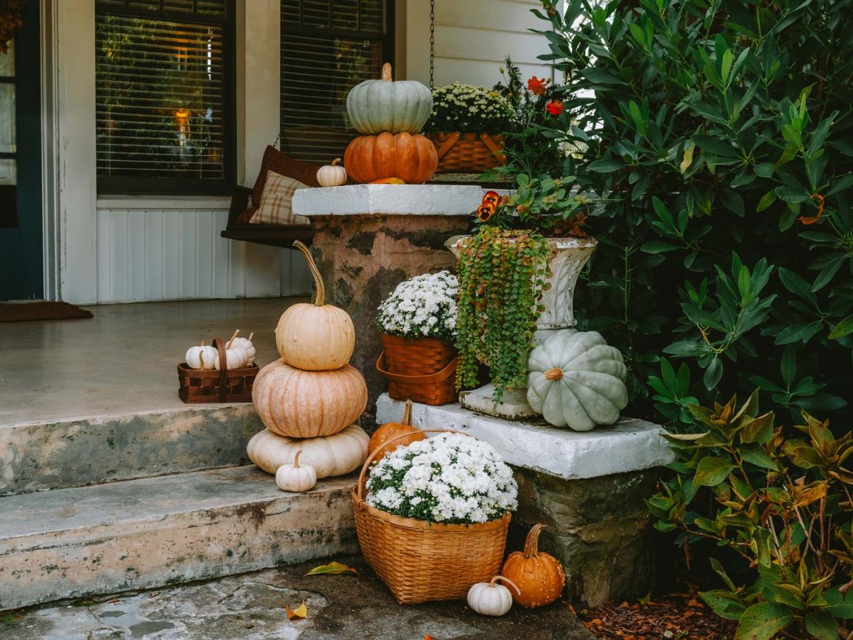 pumpkins and mums in baskets on a front porch