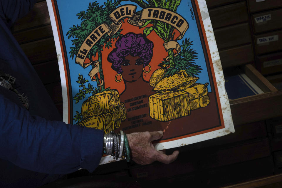 Sara Vega, especialista de la Cinemateca cubana, muestra un poster promocional sobre el arte del tabaco durante una entrevista en la Cinemateca en La Habana, el martes 11 de julio de 2023. El listado de Memoria del Mundo de la UNESCO ahora incluye una colección de seis décadas de carteles impresos en serigrafía de películas cubanas. (AP Foto/Ramón Espinosa)