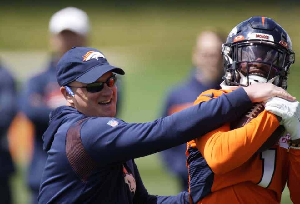 Denver Broncos head coach Nathaniel Hackett, left, tries to block a pass caught by Denver Broncos wide receiver KJ Hamler as Hamler takes part in drills during a voluntary veteran minicamp football practice Monday, April 25, 2022, at the NFL team's headquarters in Englewood, Colo. (AP Photo/David Zalubowski)