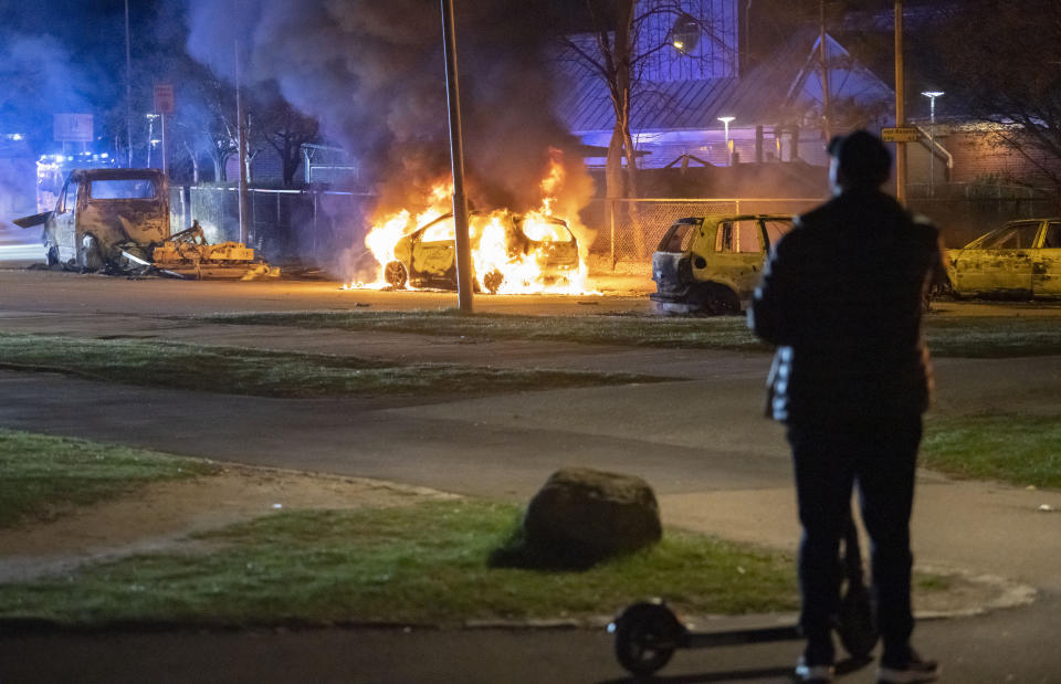 A man looks at burning cars after protests broke out at Rosengard in Malmo, Sweden, early Monday, April 17, 2022. The riots broke out following Danish far-right politician Rasmus Paludan’s meetings and planned Quran burnings in various Swedish cities and towns since Thursday. (Johan Nilsson/TT via AP)