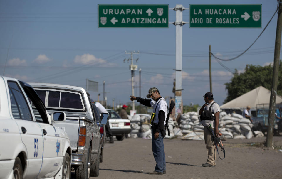 Men belonging to the Self-Defense Council of Michoacan, (CAM), inspect vehicles at a checkpoint in the entrance to the town of Nueva Italia, Mexico, Monday, Jan. 13, 2014. A day earlier the self-defenses encountered resistance as they tried to rid the town of the Knights Templar drug cartel while the government announced today that federal forces will take over security in a large swath of a western Mexico that has been hard hit by violence. (AP Photo/Eduardo Verdugo)