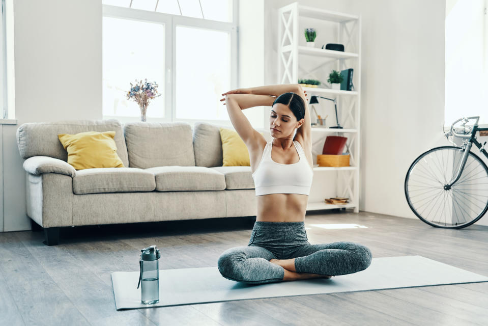 Beautiful young woman in sports clothing practicing yoga while spending time at home