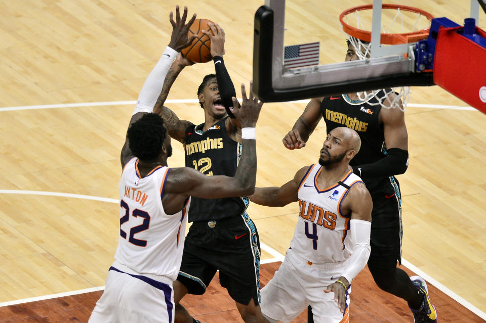 Memphis Grizzlies guard Ja Morant (12) shoots against Phoenix Suns center Deandre Ayton (22) and guard Jevon Carter (4)in the second half of an NBA basketball game Monday, Jan. 18, 2021, in Memphis, Tenn. (AP Photo/Brandon Dill)