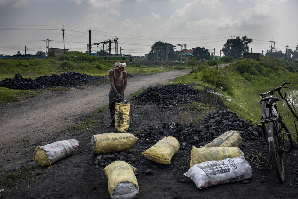 A man fills scavenged coal in sacks before selling it to traders in Dhanbad, an eastern Indian city in Jharkhand state, Friday, Sept. 24, 2021. No country will see energy needs grow faster in coming decades than India, and even under the most optimistic projections part of that demand will have to be met with dirty coal power — a key source of heat-trapping carbon emissions. (AP Photo/Altaf Qadri)