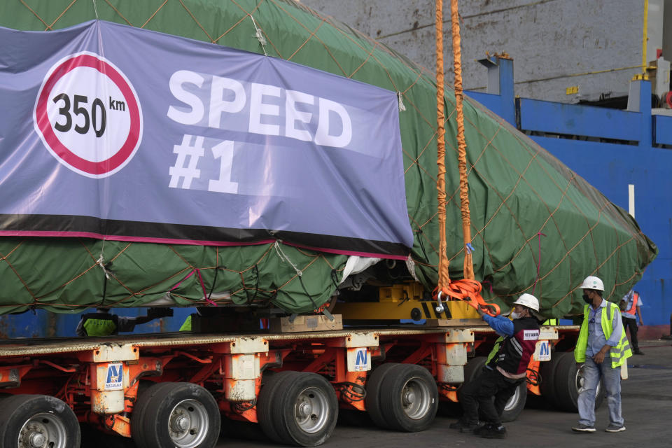 Workers secure an electric multiple unit, part of Chinese-made high-speed passenger train, onto a truck at Tanjung Priok Port in Jakarta, Indonesia, Friday, Sept. 2, 2022. The first high-speed electric train which is prepared for the Jakarta-Bandung High-Speed Railway arrived in the capital city on Friday. (AP Photo/Dita Alangkara)