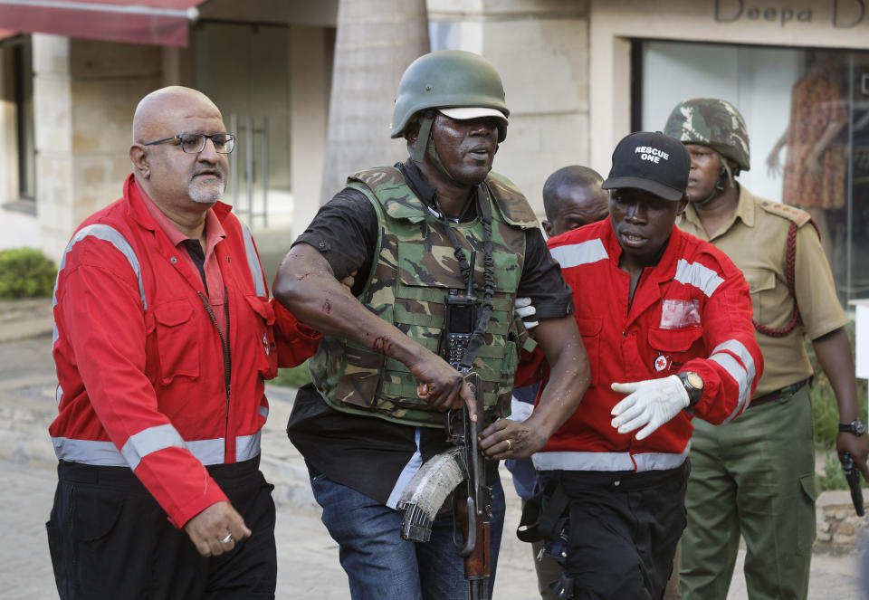 An injured member of the security forces is helped by paramedics at a hotel complex in Nairobi, Kenya Tuesday, Jan. 15, 2019. Terrorists attacked an upscale hotel complex in Kenya's capital Tuesday, sending people fleeing in panic as explosions and heavy gunfire reverberated through the neighborhood. (AP Photo/Ben Curtis)