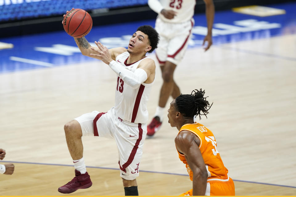 Alabama's Jahvon Quinerly (13) drives past Tennessee's Yves Pons (35) in the first half of an NCAA college basketball game in the Southeastern Conference Tournament Saturday, March 13, 2021, in Nashville, Tenn. (AP Photo/Mark Humphrey)