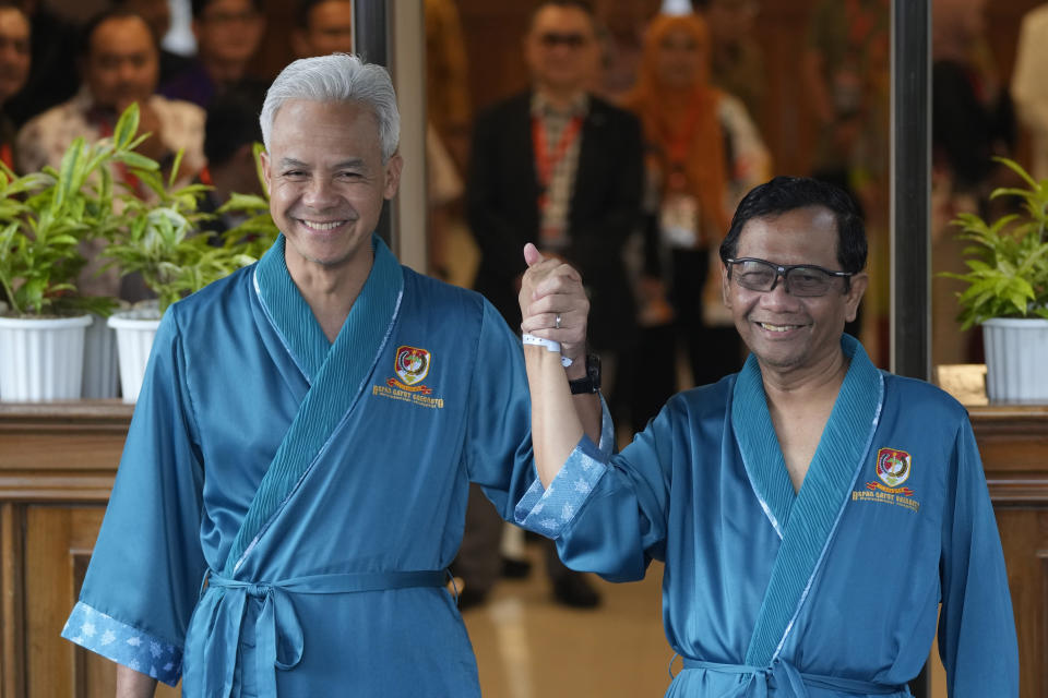 Presidential candidate Ganjar Pranowo, left, and his running mate Mohamad Mahfud, popularly known as Mahfud MD, greet reporters prior to the medical check up required for their candidacy in the upcoming presidential election, at Gatot Subroto Army Hospital in Jakarta, Indonesia, Sunday, Oct. 22, 2023. The world's third-largest democracy is holding its legislative and presidential elections on Feb. 14, 2024. (AP Photo/Dita Alangkara)