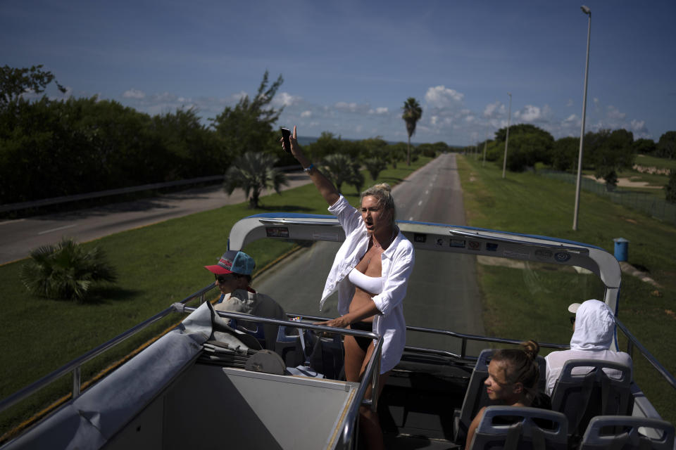 Russian tourists wave from a tour bus while on a city tour of Varadero, Cuba, Wednesday, Sept. 29, 2021. Authorities in Cuba have begun to relax COVID restrictions in several cities like Havana and Varadero. (AP Photo/Ramon Espinosa)