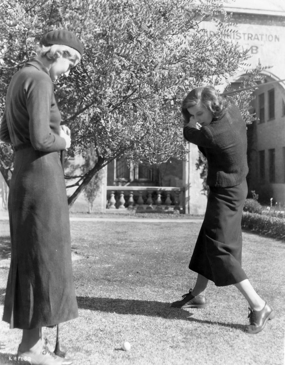 Actress Katharine Hepburn plays a game of golf with a friend.