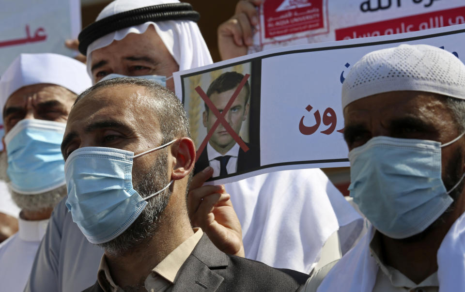 Dozens of Islamic scholars hold pictures of French President Emmanuel Macron during a protest against the publishing of caricatures of the Prophet Muhammad they deem blasphemous, in front of the French Cultural center in Gaza City, Monday, Oct. 26, 2020. (AP Photo/Adel Hana)