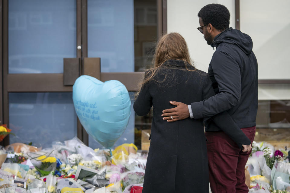 A daughter of Conservative MP Sir David Amess, is comforted as she views flowers and tributes left for her late father, at Belfairs Methodist Church, where he died after being stabbed several times during a constituency surgery on Friday, in Leigh-on-Sea, Essex, England, Monday, Oct. 18, 2021. A 25-year-old British man with Somali heritage, Ali Harbi Ali, is being held under the Terrorism Act on suspicion of murder in David Amess' killing. Police say the suspect appears to have acted alone and may have had a “motivation linked to Islamist extremism.” (Aaron Chown/PA via AP)