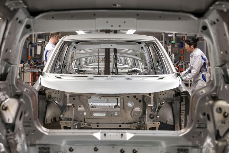 FILE- In this Tuesday, Feb. 25, 2020 file photo, workers complete an electric car ID.3 body at the assembly line during a press tour at the plant of the German manufacturer Volkswagen AG (VW) in Zwickau, Germany. The coronavirus has cancelled business plans all over the world but Europe's push into electric cars isn't one of them. Sales of battery-powered and hybrid cars have held up despite a deeply painful recession, mainly thanks to the action of governments. (AP Photo/Jens Meyer, file)