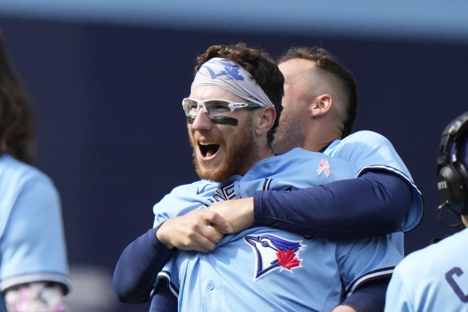 Toronto Blue Jays' Danny Jansen, center left, is hugged by teammate Matt Chapman after hitting a winning two-run single against the Atlanta Braves during ninth-inning baseball game action in Toronto, Ontario, Sunday, May 14, 2023. (Frank Gunn/The Canadian Press via AP)