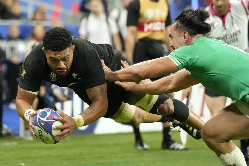 New Zealand's Ardie Savea, left, dives over the line to score a try despite Ireland's James Lowe during the Rugby World Cup quarterfinal match between Ireland and New Zealand at the Stade de France in Saint-Denis, near Paris Saturday, Oct. 14, 2023. (AP Photo/Christophe Ena)