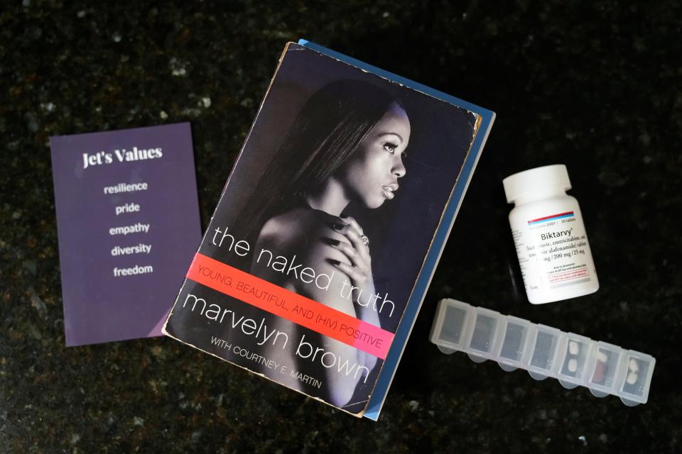 Jet Jama, who identifies as gay and nonbinary, uses a collection of items to cope with an HIV diagnosis. From left, are a set of values they live by that they came up with at a leadership workshop, a book by Marvelyn Brown called “The Naked Truth” and Biktarvy medication to reduce the spread of the disease.