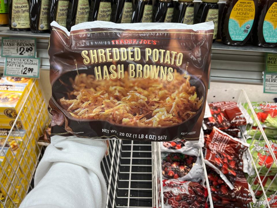 hand holding up a bag of frozen shredded potato hash browns at trader joes