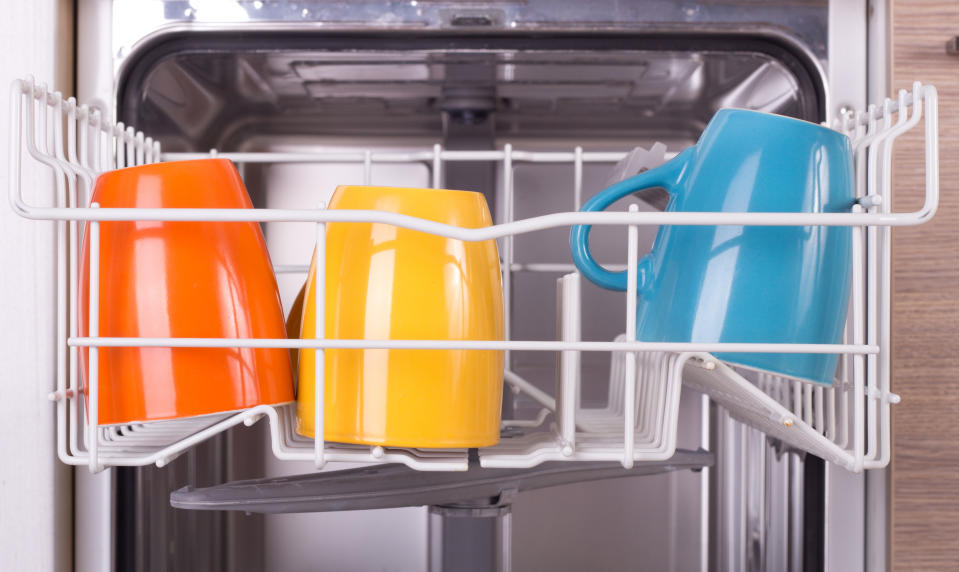 Close up of colorful cups in open dishwasher in kitchen