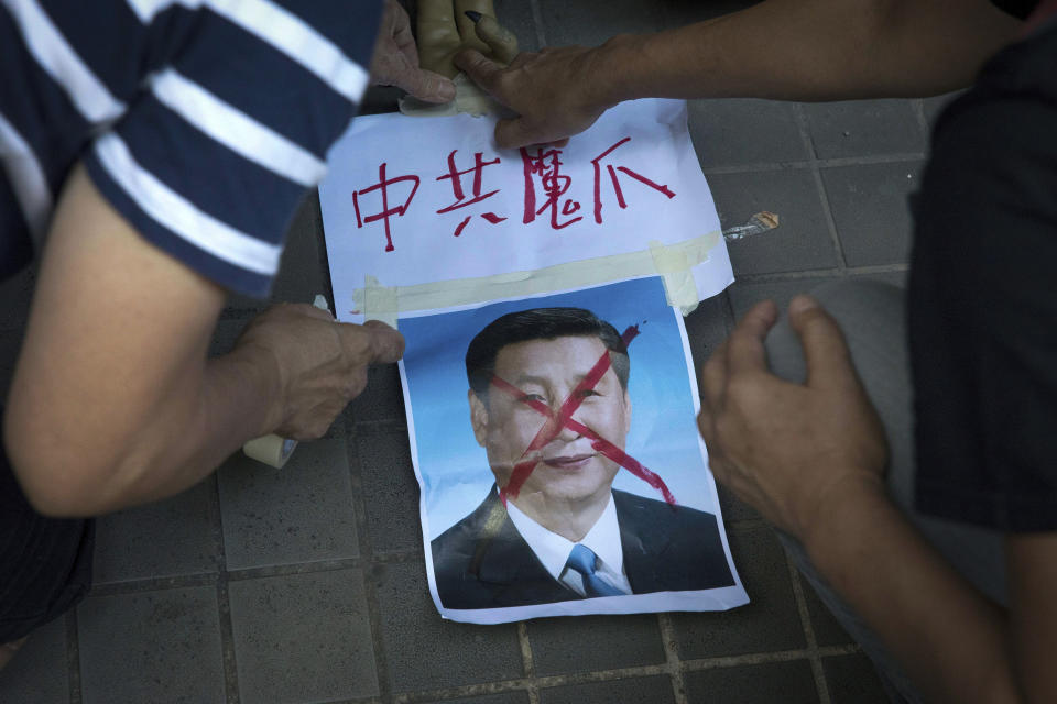 FILE - In this Saturday, July 1, 2017, file photo, pro-democracy activists paste the words "Chinese Communist Demon Claws" on a defaced photo of Chinese President Xi Jinping before attempting to march in protest towards the venue where official ceremonies are held to mark the 20th anniversary of Chinese rule over Hong Kong in Hong Kong. (AP Photo/Ng Han Guan, File)