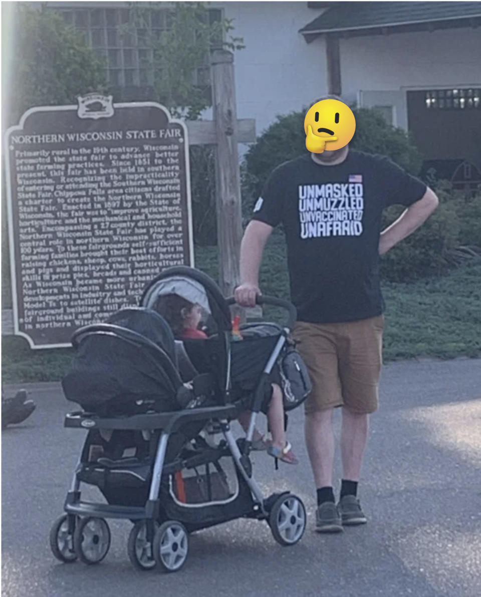 A man pushing a stroller and wearing a shirt that says "unmasked, unmuzzled, unvaccinated, unafraid"