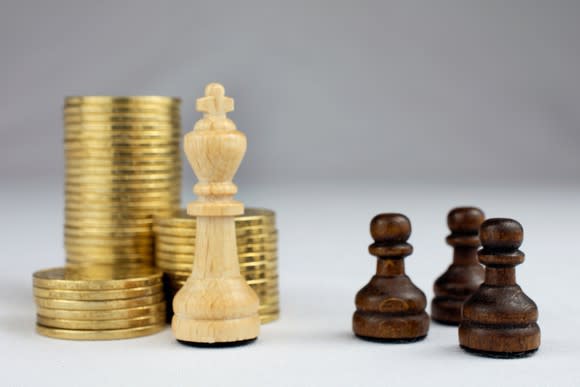 Chess pieces in front of stacked gold coins