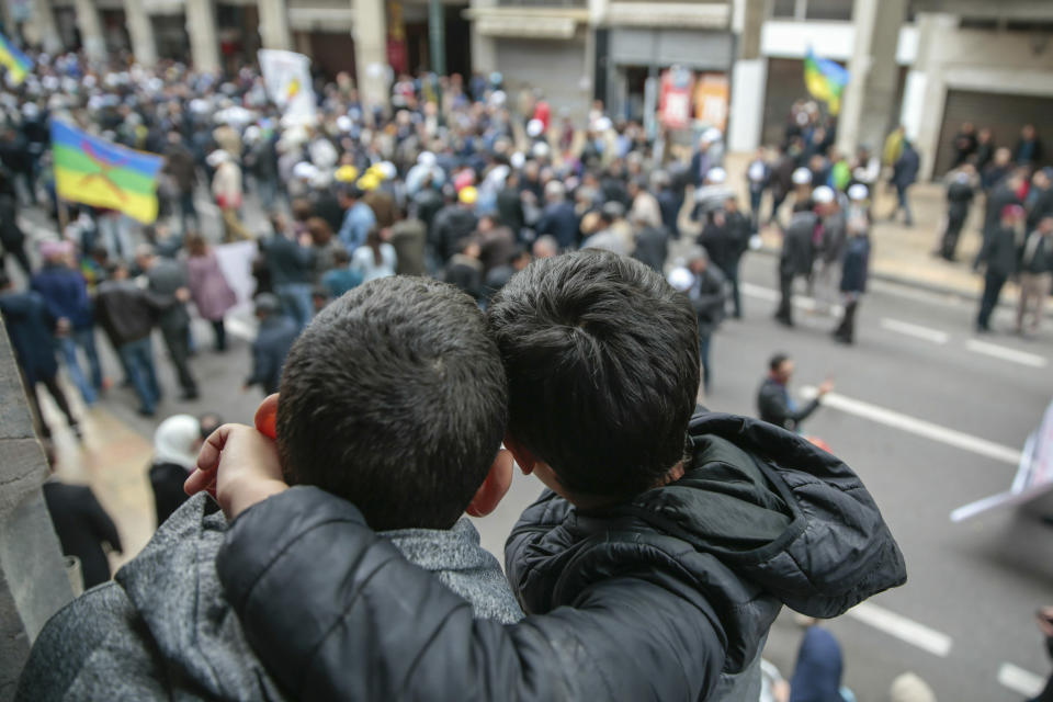 Young boys observe as thousands of Moroccans take part in a demonstration in Rabat, Morocco, Sunday, April 21, 2019. Protesters are condemning prison terms for the leader of the Hirak Rif protest movement against poverty and dozens of other activists. (AP Photo/Mosa'ab Elshamy)