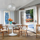 <p>Midcentury modern style rules this roost, where wooden barrel-back chairs and a textured bar cart warm up a sleek marble-top table with a tulip base. Blue surfboard wall art and the subtlest shade of blue paint on the wall are sweet salutes to the ocean just steps away.</p> <p><strong>Idea Spotlight</strong></p> <p>Bring down the house with glam lighting. A bold silver and mother-of-pearl chandelier contributes to the groovy vibes of the Malibu mobile home dining room, without straying too far from the space’s organic elements. </p>