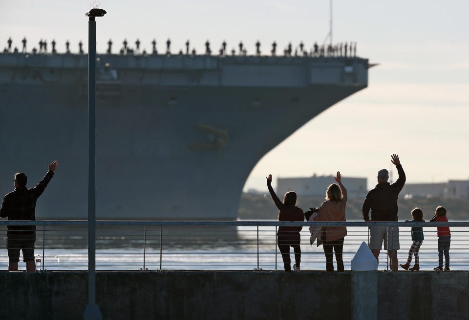 Families wave to the aircraft carrier USS Abraham Lincoln (CVN-72) as it deploys from San Diego, Calif., on Monday, Jan. 3, 2022. The USS Abraham Lincoln deployed Monday from San Diego under the command of Capt. Amy Bauernschmidt, the first woman to lead a nuclear carrier in U.S. Navy history. (K.C. Alfred/The San Diego Union-Tribune via AP)