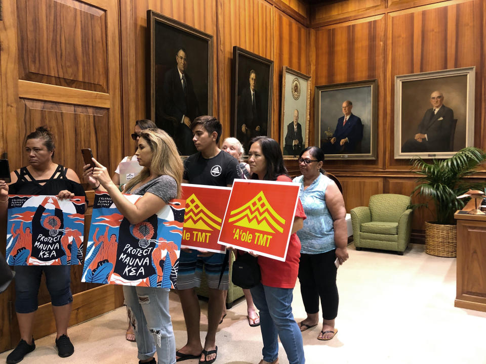 Opponents of a giant telescope planned for Hawaii's tallest mountain listen to a protest leader talk to reporters in the governor's office in Honolulu on Friday's Sept. 13, 2019. State officials are concerned about hateful language used on both sides of the heated debate over whether to build the Thirty Meter Telescope. (AP Photo/Jennifer Sinco Kelleher)