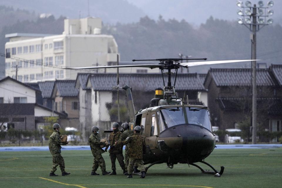 Members of the Japan Ground Self-Defense Force load relief goods into its helicopter before taking off from a temporary landing site in Wajima in the Noto peninsula, facing the Sea of Japan, northwest of Tokyo, Saturday, Jan. 6, 2024, following Monday's deadly earthquake. (AP Photo/Hiro Komae)