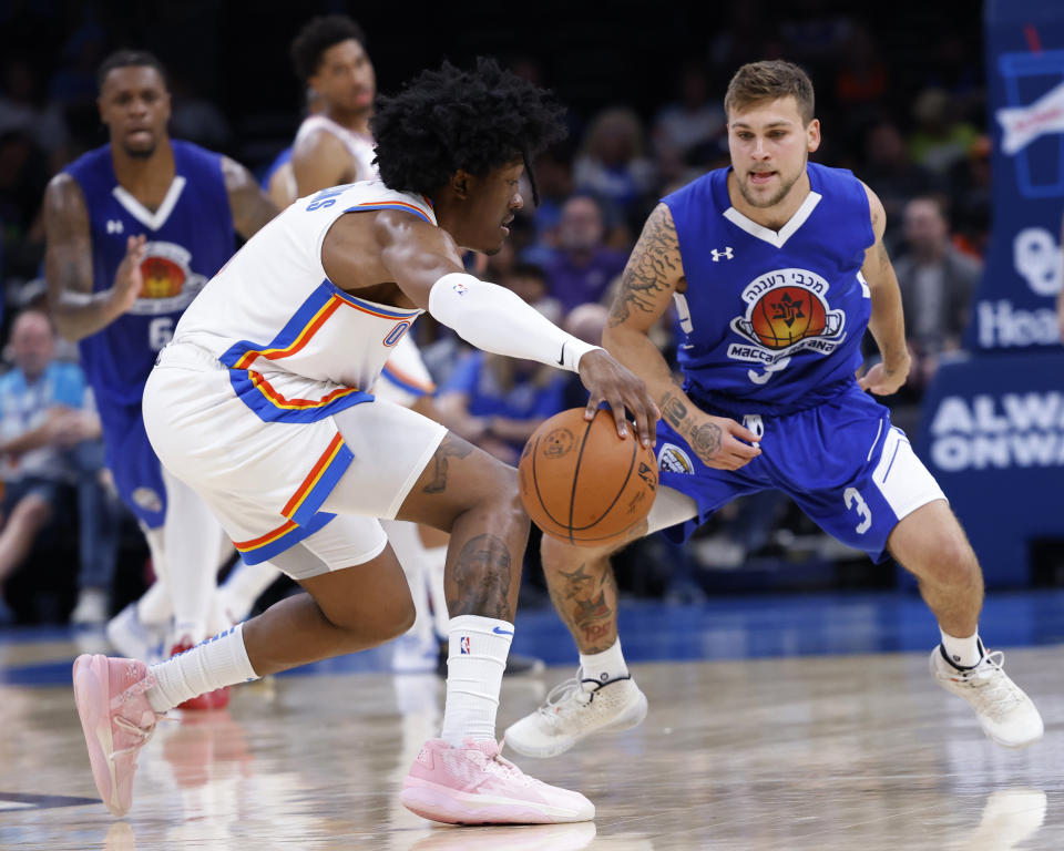 Oklahoma City Thunder forward Jaylin Williams, left, goes against Maccabi Ra'anana point guard Alex Leder during the first half of a preseason NBA basketball game, Sunday, Oct. 9, 2022, in Oklahoma City. (AP Photo/Garett Fisbeck)